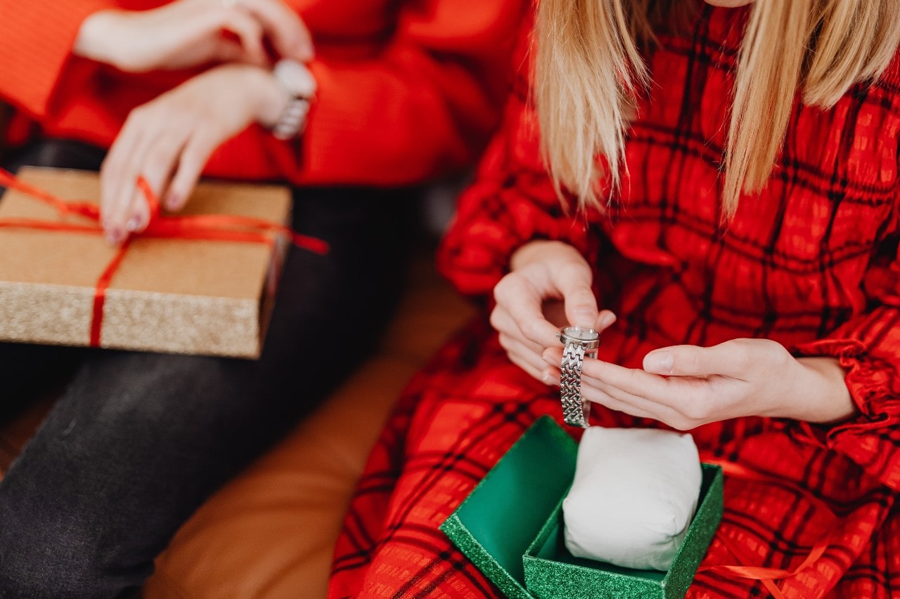 A view of a woman in a festive plaid nightgown inspecting a luxury watch she received as a Christmas gift.