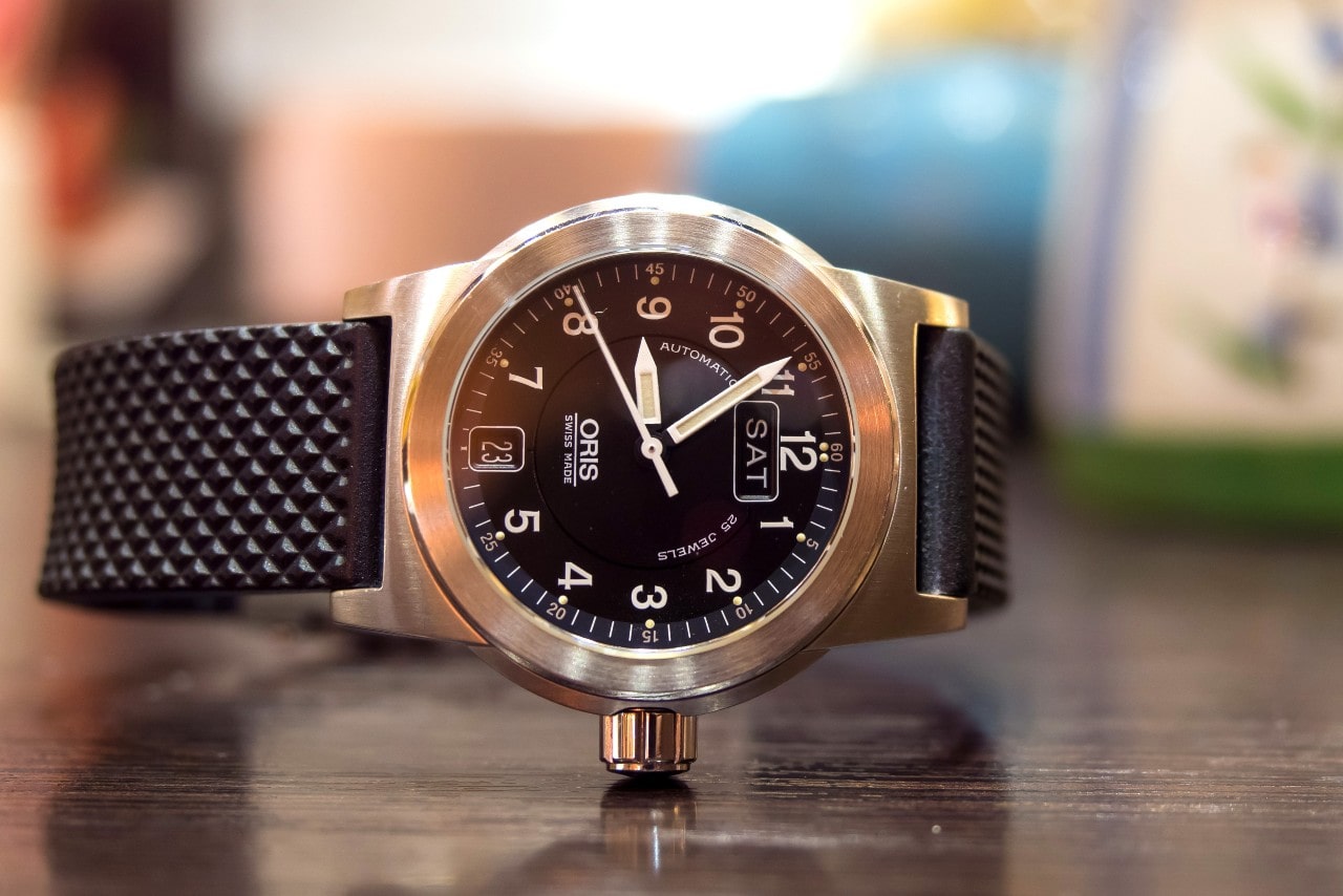 A close-up of an Oris watch displayed on its side atop a wooden surface.