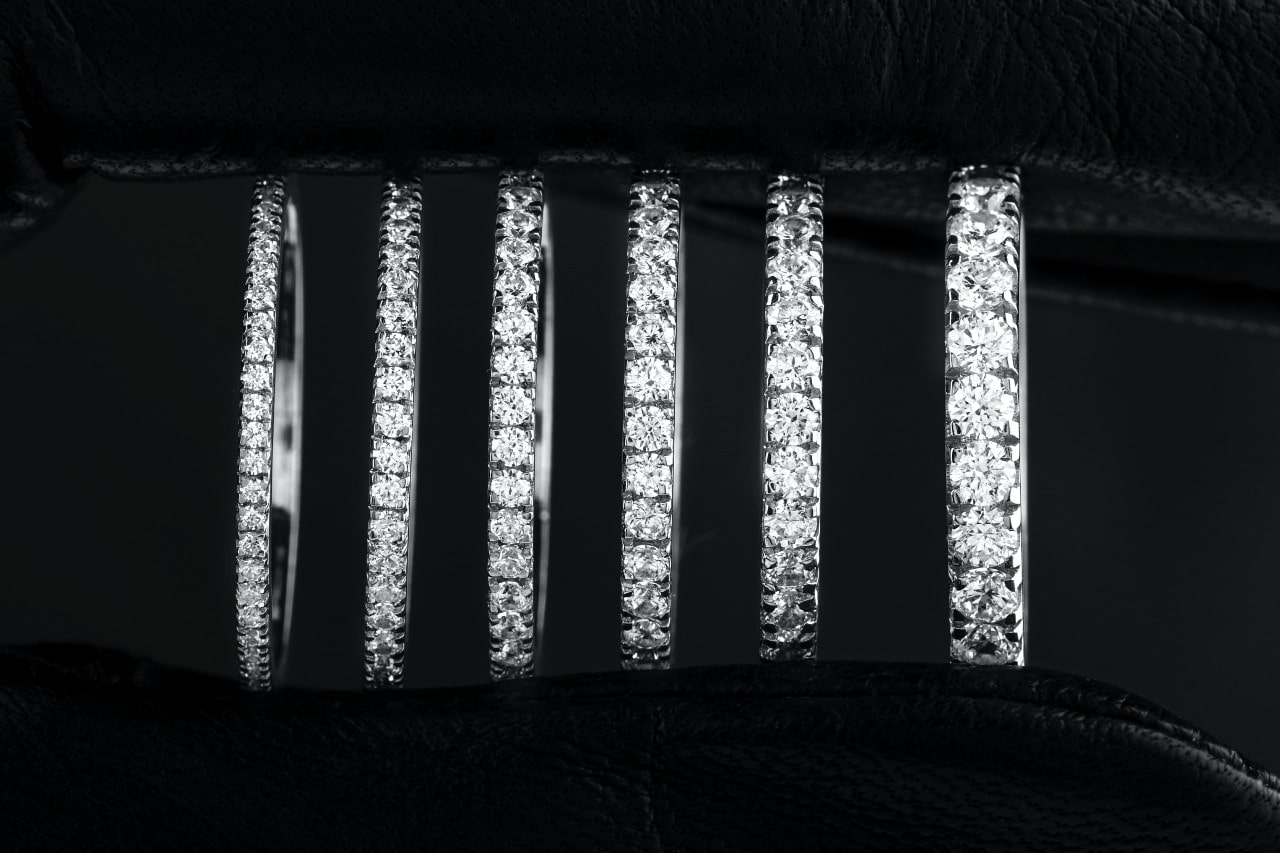 A close-up of a selection of side stone wedding bands of different widths on a black velvet background. A close-up of a selection of side stone wedding bands of different widths on a black velvet background.