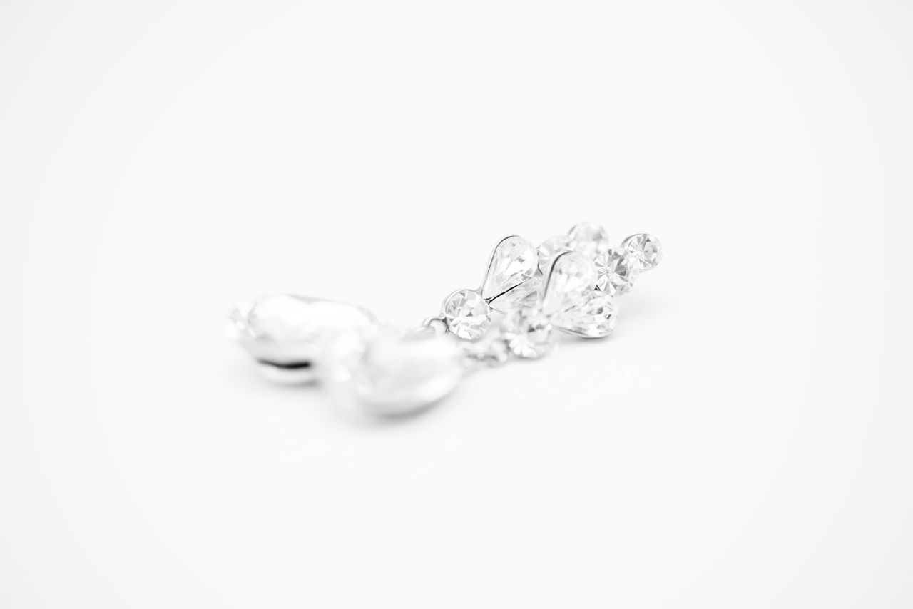 A close up of white gold diamond and pearl drop earrings.