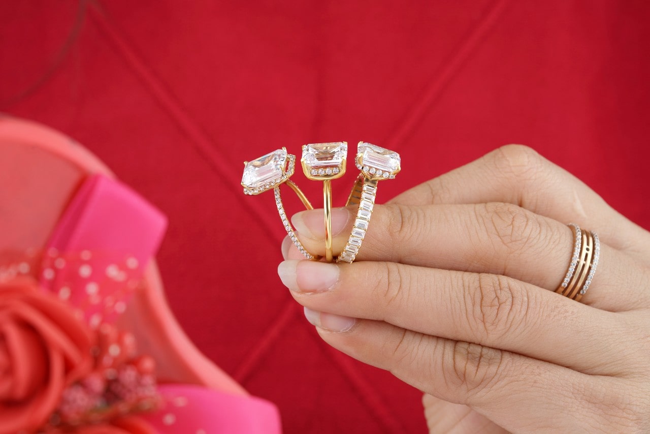 A woman holding three yellow gold engagement rings