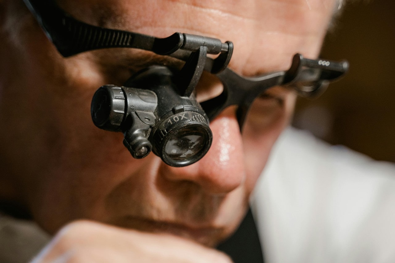 A close-up of a person wearing magnifying eyeglasses inspecting something closely A close-up of a person wearing magnifying eyeglasses inspecting something closely
